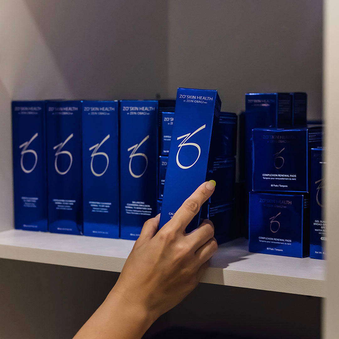 hand grabbing ZO Skin Health products off shelf